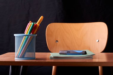 Siyah arka plan üzerine okulda masa mavi metal sepetteki renkli kalemler