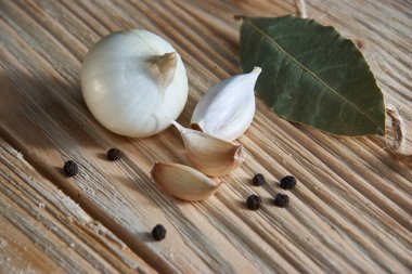 soğan, sarımsak, kara biber ve defne yaprağı ahşap bir masa üzerinde