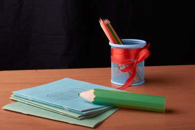 Yeşil büyük kalem ve siyah arka plan üzerine izole masa üzerinde boya kalemi ile metal Kupası