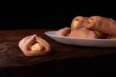 Ev yapımı çörekler ahşap arka plan üzerinde süzme peynir ile doldurulmuş. Makro fotoğraf. Seçici odak.