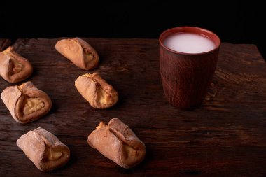 Süzme peynir ve ahşap masa arka plan üzerinde süt ile tatlılar. Resepsiyon mini pies. Rustik tarzı.