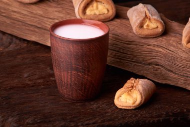 Süzme peynir ve ahşap masa arka plan üzerinde süt ile tatlılar. Resepsiyon mini pies. Rustik tarzı.