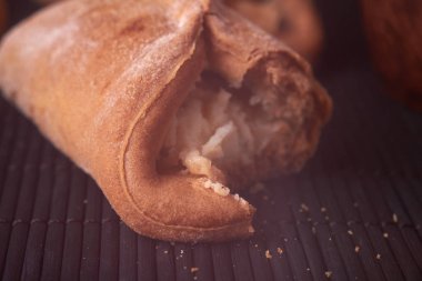 Süzme peynirli çerezlerini alınan bir ısırık. Ev yapımı çörekler ahşap arka plan üzerinde süzme peynir ile doldurulmuş. Makro fotoğraf. Seçici odak.