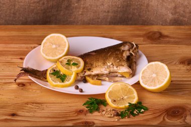 Kavrulmuş sazan ile ahşap masa tabakta dorado balık maydanoz, chives ve limon ile