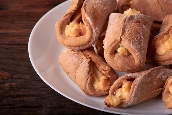 Ev yapımı çörekler ahşap arka plan üzerinde süzme peynir ile doldurulmuş. Seçici odak.