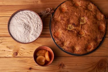 kayısı pasta ve bir kase un ve diğer malzemeler ahşap tablo