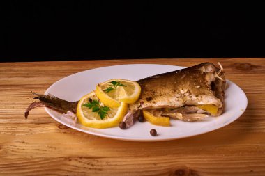 Kavrulmuş sazan ile ahşap masa tabakta dorado balık maydanoz, chives ve limon ile