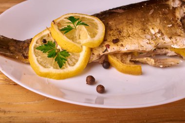 Otlar ve ahşap zemin, üstten görünüm üzerine limon ile ızgara balık. Akdeniz lüks deniz ürünleri kavramı