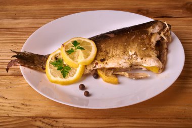 Kavrulmuş sazan ile ahşap masa tabakta dorado balık maydanoz, chives ve limon ile