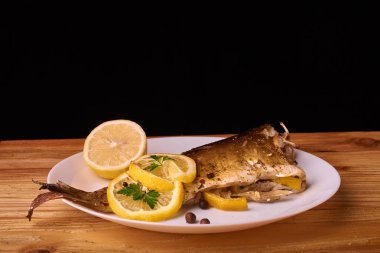 limon dilimleri, baharat ve fırın tepsisine, taze biberiye ile lezzetli kavrulmuş sazan balık yukarıdan görüntülemek