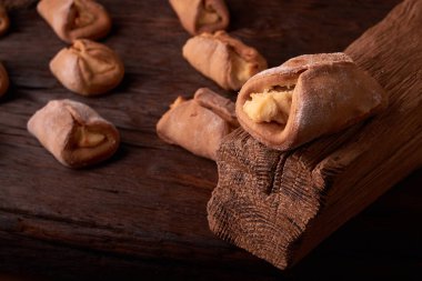 Ev yapımı çörekler ahşap arka plan üzerinde süzme peynir ile doldurulmuş. Seçici odak.