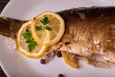 limon dilimleri, baharat ve fırın tepsisine, taze biberiye ile lezzetli kavrulmuş sazan balık yukarıdan görüntülemek