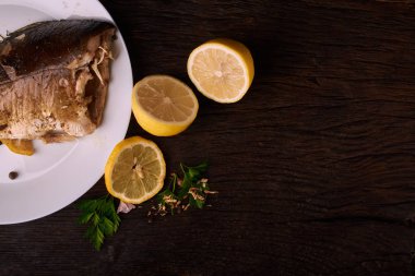 Otlar ve ahşap zemin, üstten görünüm üzerine limon ile ızgara balık. Akdeniz lüks deniz ürünleri kavramı
