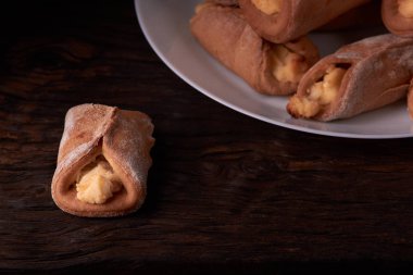 Ev yapımı çörekler ahşap arka plan üzerinde süzme peynir ile doldurulmuş. Seçici odak.