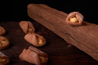 Ev yapımı çörekler ahşap arka plan üzerinde süzme peynir ile doldurulmuş. Seçici odak.