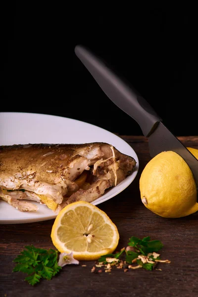 Düzenlenen lemonwith siyah bıçak ve plaka baharat ve otlar ile ızgara balık sos ile