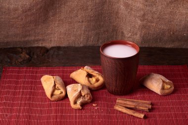 Süzme peynirli çerezlerini alınan bir ısırık. Ev yapımı çörekler süzme peynir ve kil bardak süt ahşap zemin ile doldurulmuş. Makro fotoğraf.