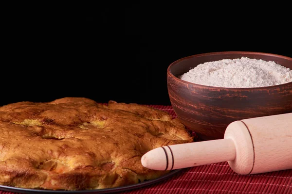 Siyah ahşap bir zemin üzerine un ve kayısı kek ile bir kase