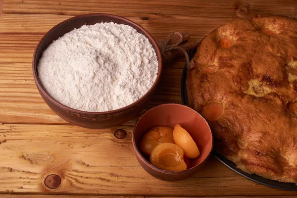 kayısı pasta ve bir kase un ve diğer malzemeler ahşap tablo