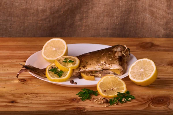 limon dilimleri, baharat ve fırın tepsisine, taze biberiye ile lezzetli kavrulmuş sazan balık yukarıdan görüntülemek