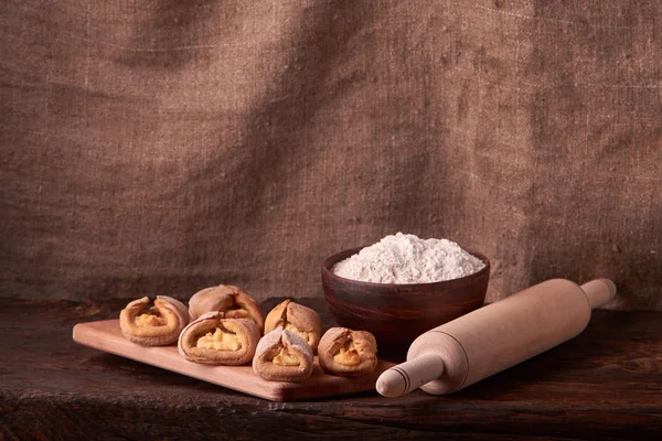 Kil kase un, oklava ve süzme peynir kurabiye ile. Cookie koyu arka plan üzerinde pişirme.