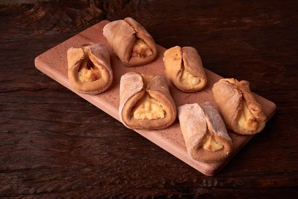 Kurabiyeleri süzme peynir ile fırında, ahşap masa ve siyah arka plan üzerinde. Yakın, seçici odak.