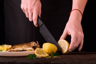 Tanınmayan kadın kesme taze limon yemek mutfakta, eller yakın çekim görünümünü siyah arka plan üzerine için ahşap tahta üzerinde