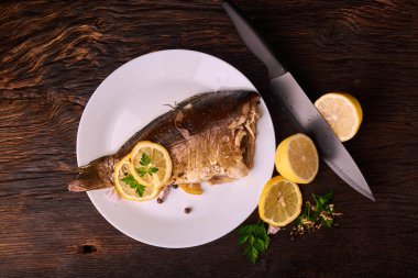 limon dilimleri, baharat ve fırın tepsisine, taze biberiye ile lezzetli kavrulmuş sazan balık yukarıdan görüntülemek