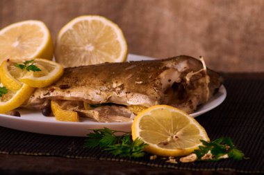 Limon, baharatlar ve otlar ahşap arka plan üzerinde beyaz tabakta Fırında Balık