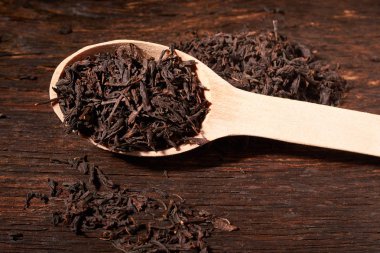 Tahta kaşık çay siyah yapraklarda siyah koyu ahşap masa