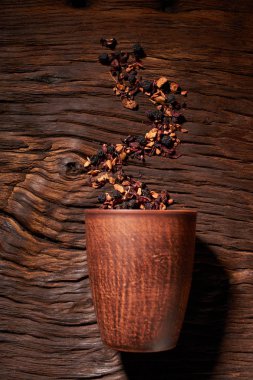 Kupası ve ahşap bir masaya izole kuru çay yaprakları