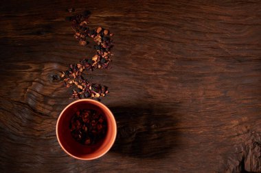 Kupası ve ahşap bir masaya izole kuru çay yaprakları