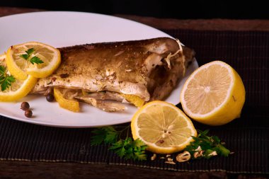 limon dilimleri, baharat ve fırın tepsisine, taze biberiye ile lezzetli kavrulmuş sazan balık yukarıdan görüntülemek