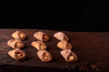 Ev yapımı çörekler ahşap arka plan üzerinde süzme peynir ile doldurulmuş. Seçici odak.