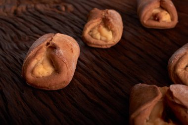 Ev yapımı çörekler ahşap arka plan üzerinde süzme peynir ile doldurulmuş. Seçici odak.