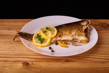 limon dilimleri, baharat ve fırın tepsisine, taze biberiye ile lezzetli kavrulmuş sazan balık yukarıdan görüntülemek