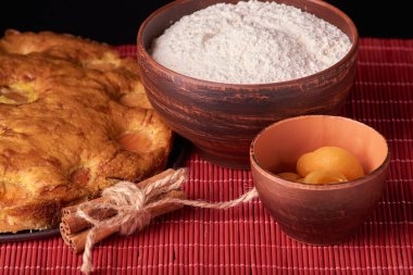 Bir koyu ahşap masa Amerikan kayısı pasta, malzemeler ve araçlar