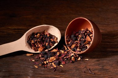 bir ahşap masa ve siyah arka plan üzerinde bir kil kase meyve çayı.