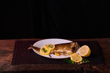 Kavrulmuş sazan ile ahşap masa tabakta dorado balık maydanoz, chives ve limon ile