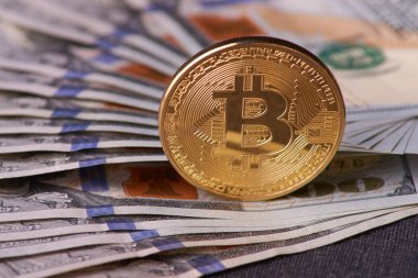 Güzel gri bir arka plan üzerinde faturaları 100 dolar ve altın sikke bitcoin düzenlenmiş. Bitcoin cryptocurrency. Anonim