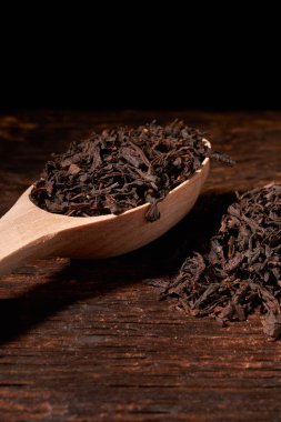 Tahta kaşık çay siyah yapraklarda siyah koyu ahşap masa