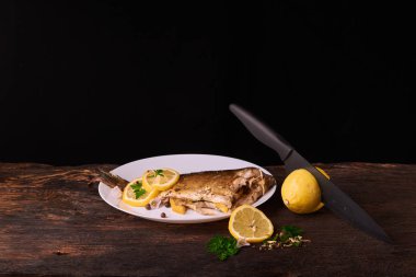 Düzenlenen lemonwith siyah bıçak ve plaka baharat ve otlar ile ızgara balık sos ile