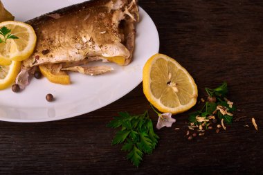 limon dilimleri, baharat ve fırın tepsisine, taze biberiye ile lezzetli kavrulmuş sazan balık yukarıdan görüntülemek