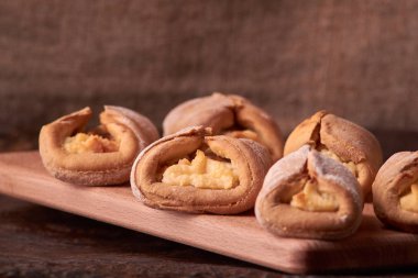 Ev yapımı çörekler ahşap arka plan üzerinde süzme peynir ile doldurulmuş. Seçici odak.