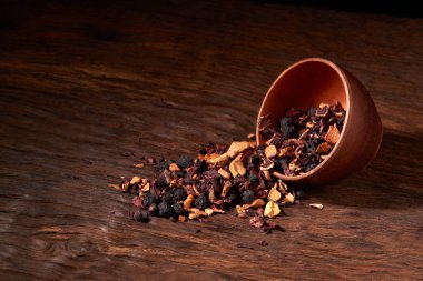 bir ahşap masa ve siyah arka plan üzerinde bir kil kase meyve çayı.