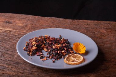 Siyah Kuru meyve çayı mavi tabak içinde tahta masada bırakır.