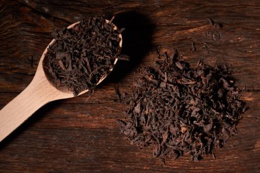 Tahta kaşık çay siyah yapraklarda siyah koyu ahşap masa