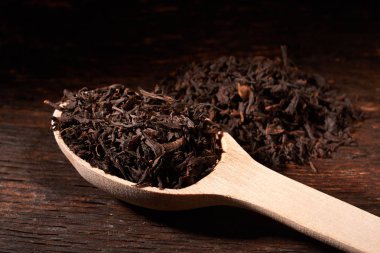 Tahta kaşık çay siyah yapraklarda siyah koyu ahşap masa