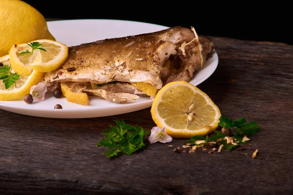 Grilled fish with herbs and lemon on wooden background, top view. Mediterranean luxurious seafood concept