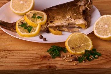 limon dilimleri, baharat ve fırın tepsisine, taze biberiye ile lezzetli kavrulmuş sazan balık yukarıdan görüntülemek